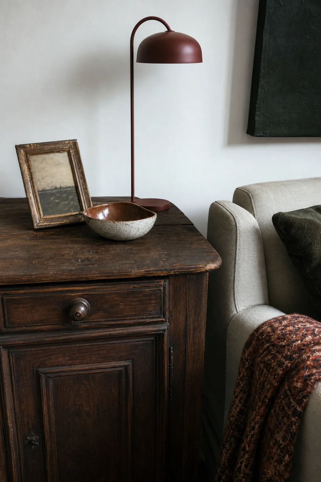 Close editorial vignette combining an old timber table, modern lamp, textile and handmade ceramic