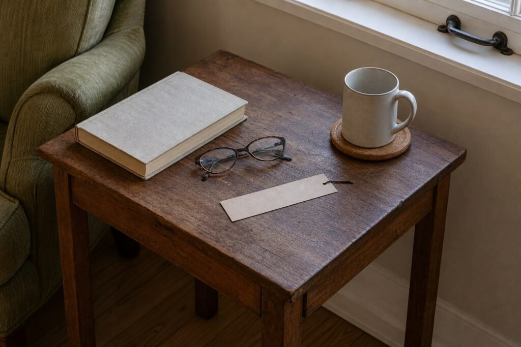 Stable side table with a current book, glasses, bookmark and mug while the window sill stays clear